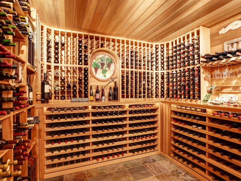Bright home wine cellar with wooden storage units and arch with bottles. Northwest, USA